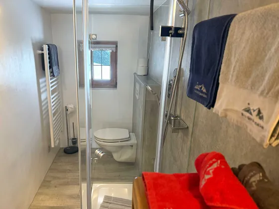 Badkamer met daglicht van Appartement 11 met handdoekradiator, handdoeken, wc-papier en raam