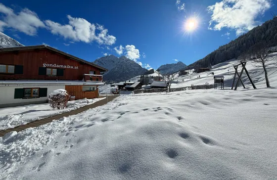 Winter view of Gondamaika with a snow-covered garden and mountains, Kleinwalsertal