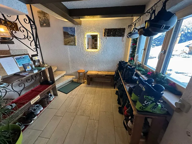 Entrance area of the house with a boot rack, ski boots, information material and a guest book — Gondamaika, Hirschegg Kleinwalsertal