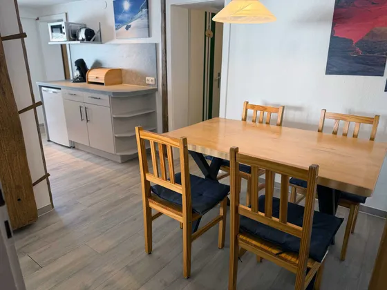 Eethoek van Appartement 11 met houten tafel, vier stoelen en zicht op de keuken