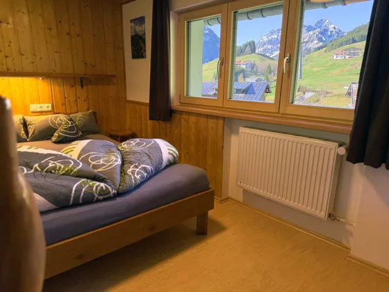 Slaapkamer 2 van Appartement 11 met bed van 160 cm, rustieke houten bekleding en balkontoegang