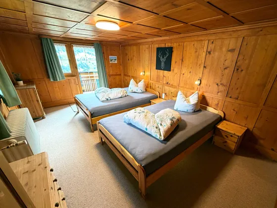 Slaapkamer 2 van Appartement 22: twee houten bedden, rustieke houten bekleding en balkontoegang