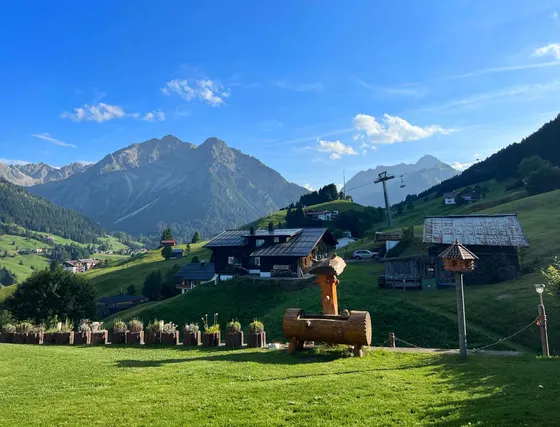 Garden with lawn, fountain and a view of Alpine villages and mountain ranges in the Kleinwalsertal
