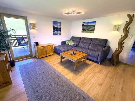 Woonkamer van Appartement 11 met bergzicht door het raam en balkontoegang