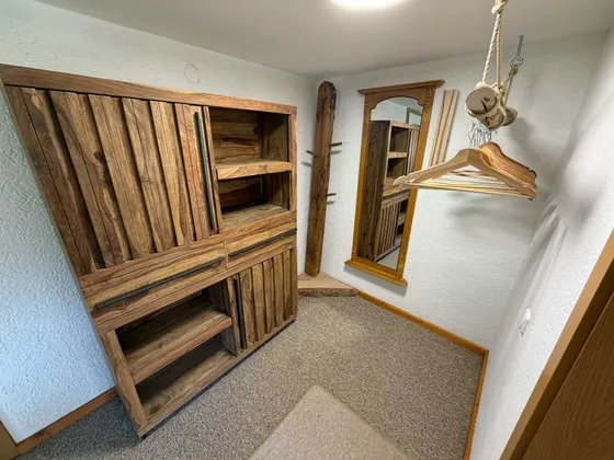 Bergruimte en garderobe in de woonruimte van Appartement 22 met houten meubels en spiegel