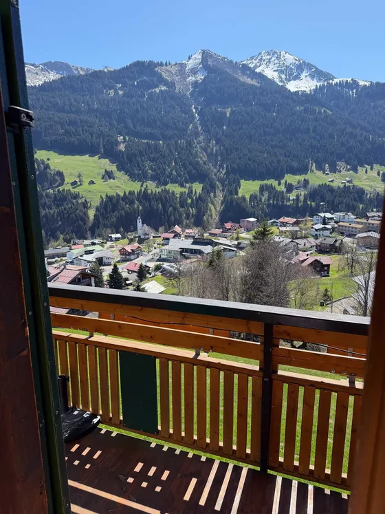 Balkon van Appartement 22 met zicht in het dal op Hirschegg, de kerk en besneeuwde bergtoppen